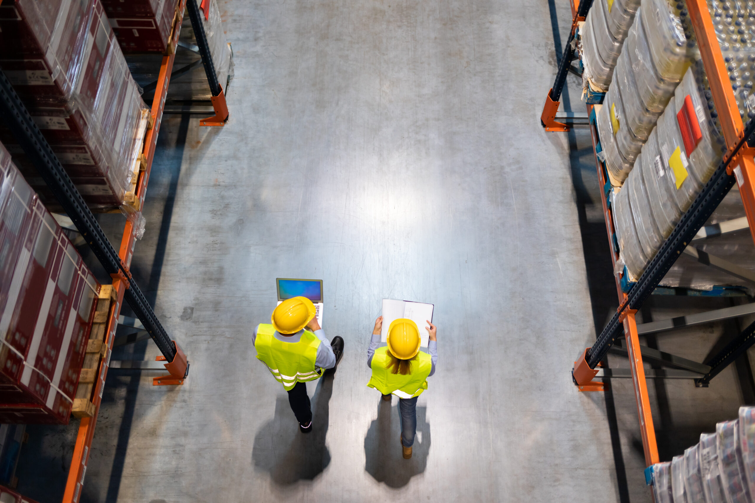 Warehouse workers consult delivery plans using laptop and electronic database